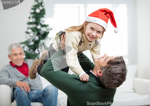 Image of Daughter Being Carried By Father During Christmas