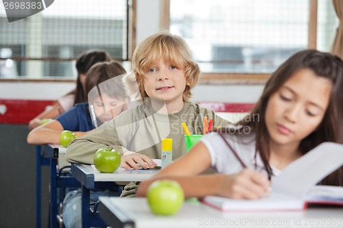 Image of Schoolboy Sitting In A Row With Classmates At Classroom