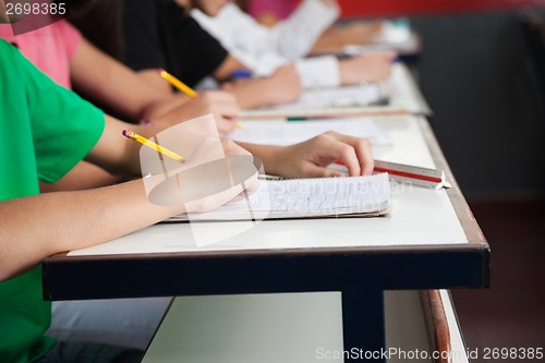 Image of High School Students Writing On Paper At Desk