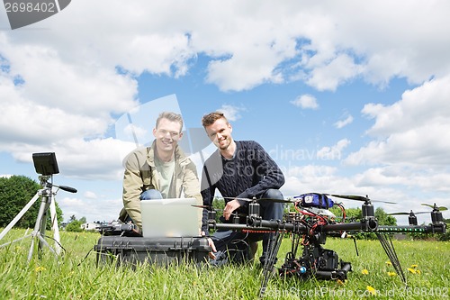 Image of Men Using Laptop Next To UAV