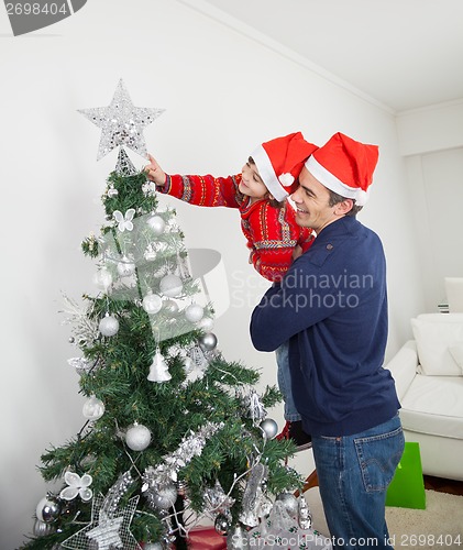 Image of Son And Father Decorating Christmas Tree