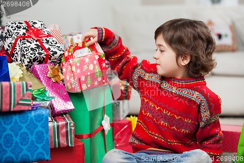 Image of Boy Sitting By Stacked Christmas Gifts