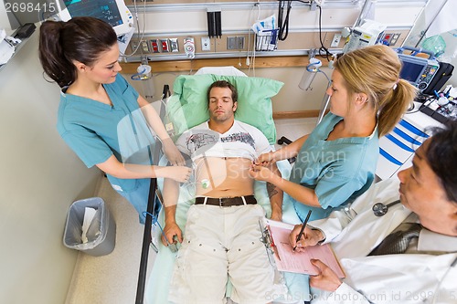 Image of Nurses And Doctor Examining Patient's Pulse In Hospital