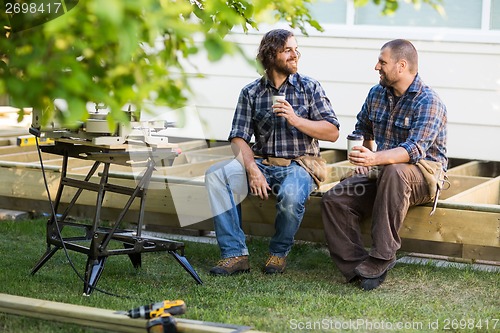 Image of Carpenters With Disposable Cups Looking At Each Other On Frame