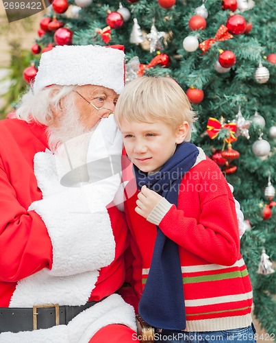 Image of Santa Claus Whispering In Boy's Ear