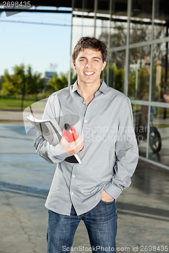 Image of Student Holding Book And Juice Bottle On Campus