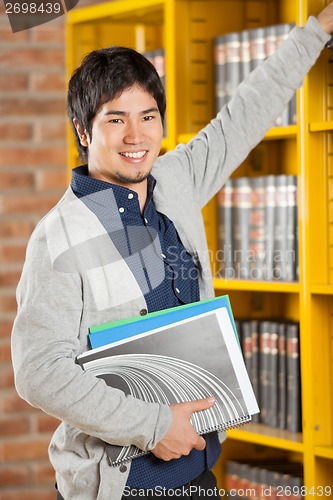 Image of Male Student Choosing Books In College Library