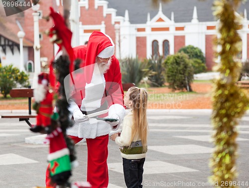 Image of Santa Claus Offering Cookies To Girl