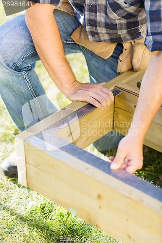 Image of Manual Worker Measuring Wood With Scale At Construction Site