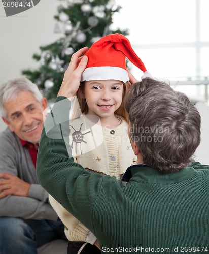 Image of Father Adjusting Girl's Santa Hat