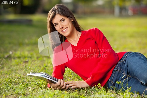 Image of Female Student With Books Relaxing On Grass At Campus