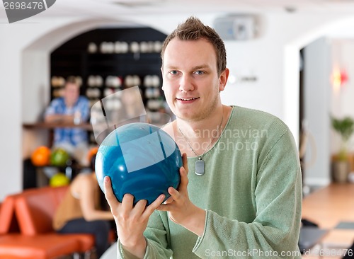 Image of Man Holding Blue Bowling Ball in Club