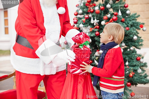 Image of Santa Claus Giving Present To Boy