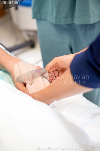 Image of Nurse Injecting Needle In Male Patient's Hand