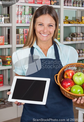 Image of Saleswoman Holding Digital Tablet And Fruits Basket