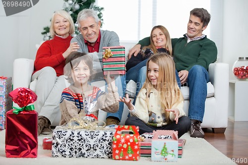 Image of Boy Holding Christmas Gift With Family In House