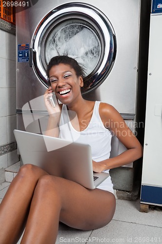 Image of Woman Using Laptop And Mobilephone In Laundry