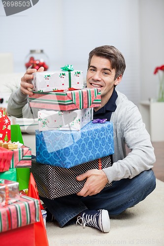 Image of Man With Stack Of Christmas Presents At Home