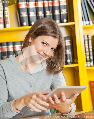 Image of Woman With Digital Tablet Sitting Against Bookshelf In Library
