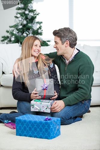 Image of Couple With Christmas Presents Sitting On Floor