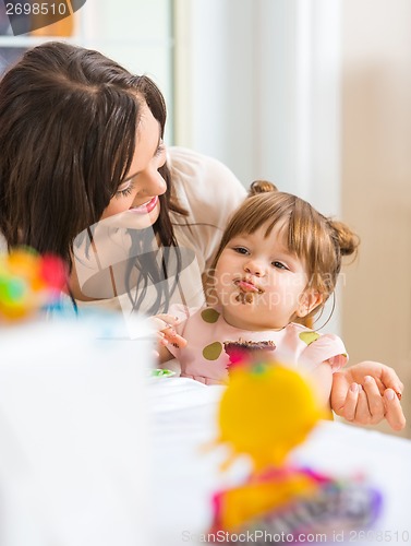 Image of Mother Looking At Daughter Eating Cupcake