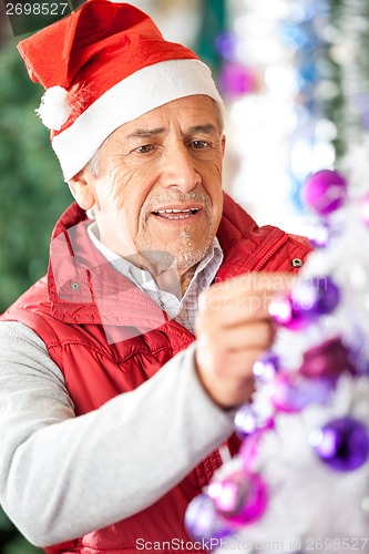 Image of Male Owner Decorating Christmas Tree At Store