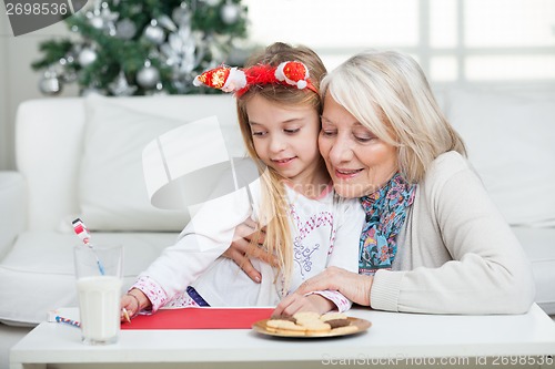 Image of Grandmother Assisting Girl In Writing Letter To Santa Claus