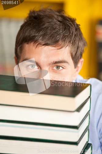 Image of Student Peeking Over Piled Books In University Library