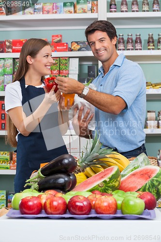 Image of Male Customer With Saleswoman Comparing Bellpepper At Supermarke
