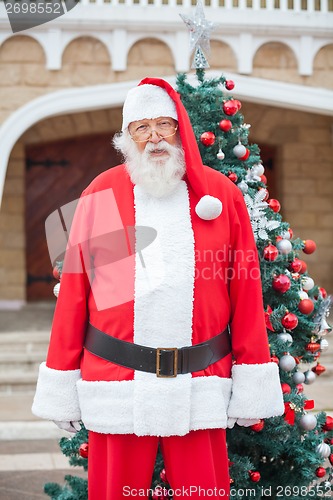 Image of Santa Claus Standing Against Christmas Tree