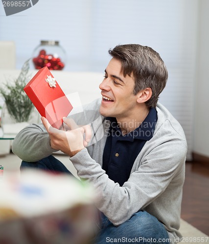 Image of Smiling Man Looking At Christmas Gift