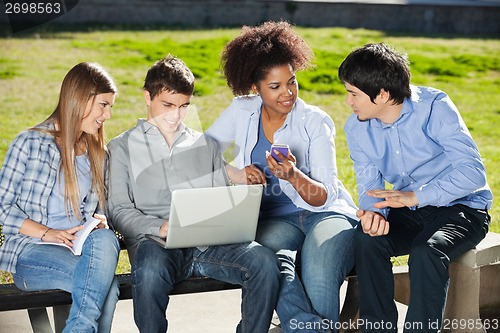 Image of Students With Laptop And Mobilephone Sitting In Campus