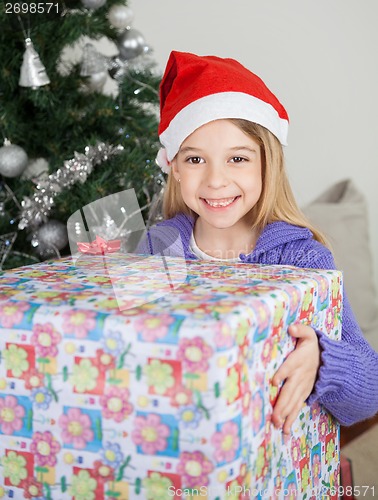 Image of Girl Holding Gift By Christmas Tree