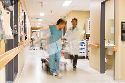 Image of Doctor And Nurse Pulling Stretcher In Hospital Corridor