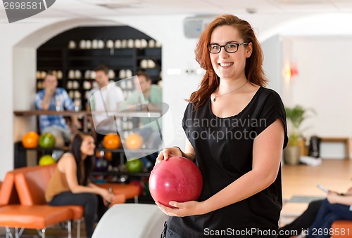 Image of Happy Young Woman Holding Bowling Ball in Club