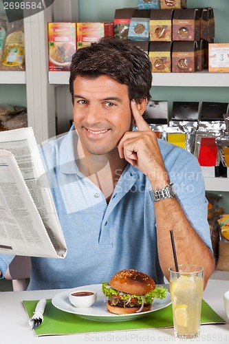 Image of Male Customer With Snacks And Newspaper In Supermarket