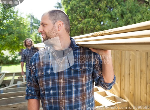 Image of Carpenters Carrying Planks At Construction Site