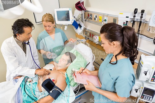 Image of Doctor And Nurses Examining Patient In Hospital