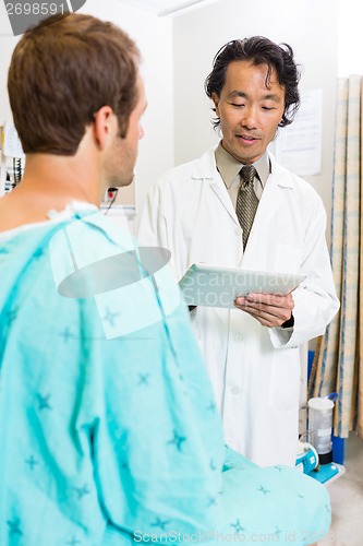 Image of Doctor Holding Digital Tablet While Discussing Medical Report Wi
