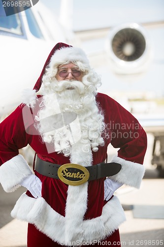 Image of Santa Standing With Hands On Hip Against Private Jet