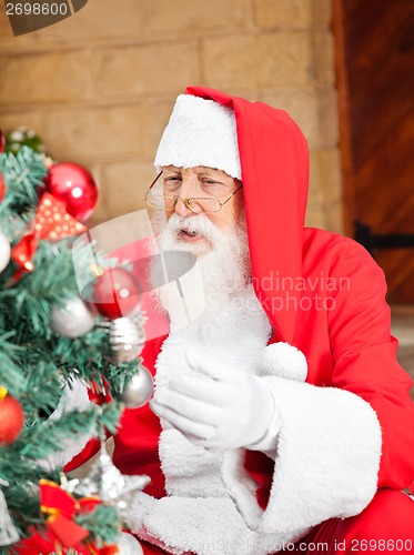 Image of Man Dressed As Santa Claus Decorating Christmas Tree
