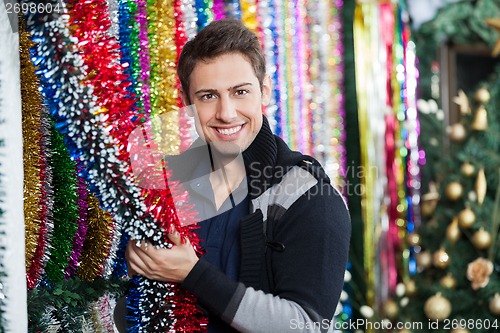 Image of Young Man Choosing Tinsels At Store