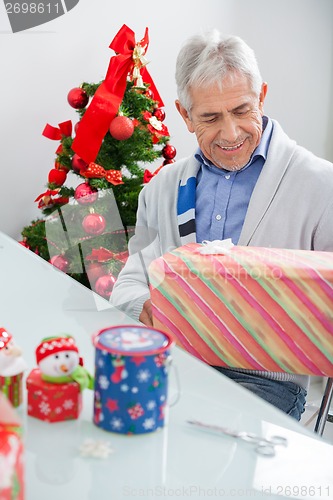Image of Man Looking At Wrapped Christmas Present