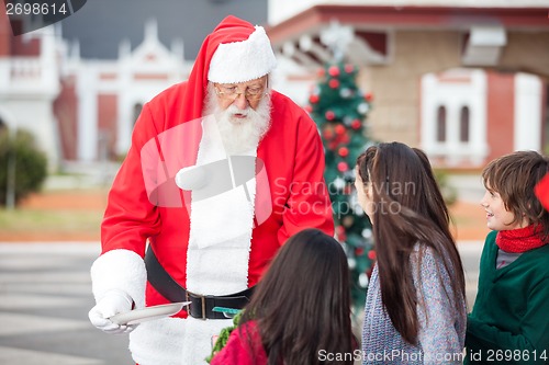 Image of Santa Claus Offering Cookies To Children