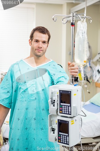 Image of Patient Holding Pole With Drip Bag And Machine In Hospital