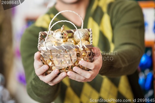 Image of Man Holding Bauble Basket In Store