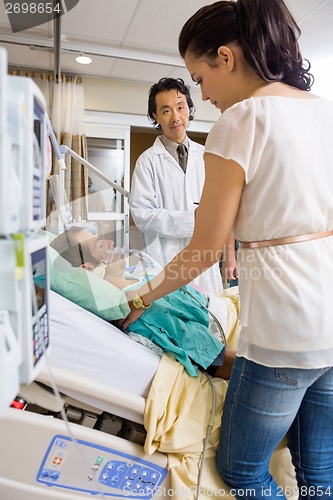 Image of Doctor Looking At Woman Standing By Patient's Bed