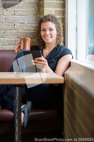 Image of Woman With Digital Tablet And Coffee Mug In Cafeteria