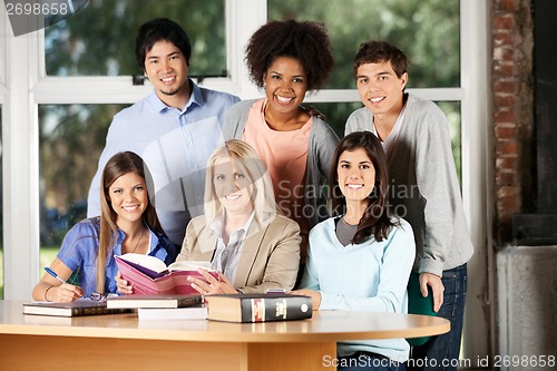 Image of Students And Teacher With Books Smiling In Classroom
