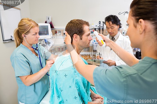 Image of Medical Team Examining Male Patient